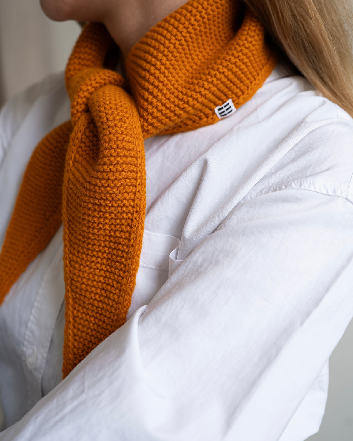 nahaufnahme von einem mini schal in orange welcher um den hals einer frau hängt