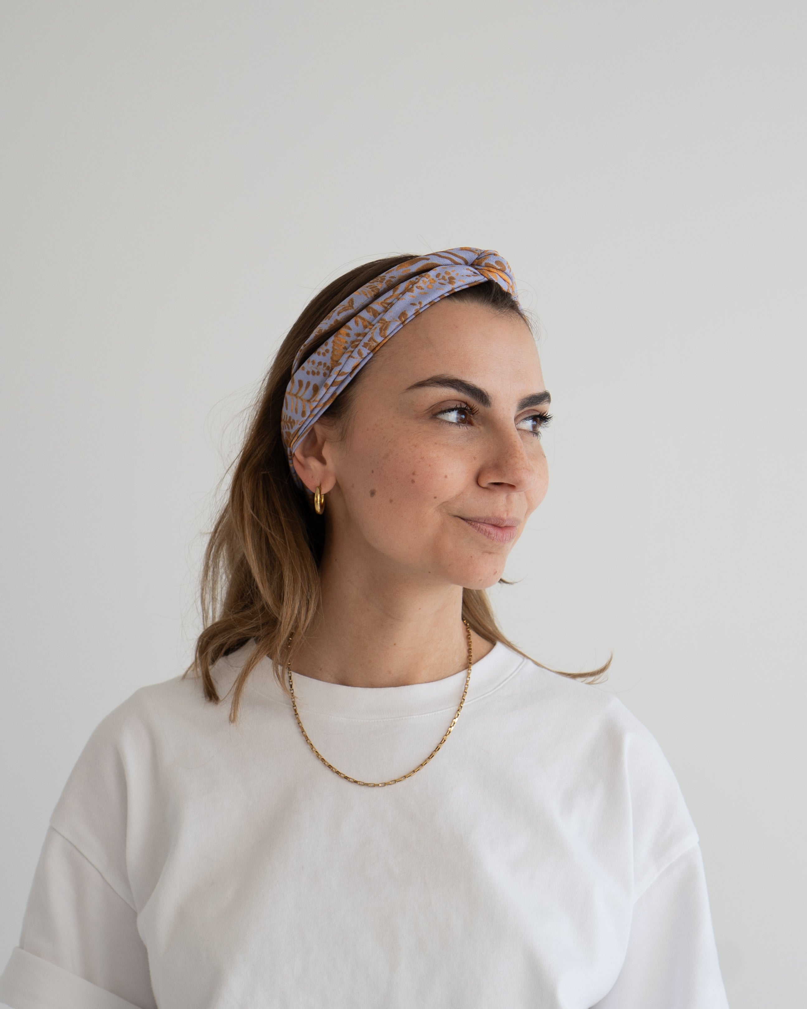 eine frau trägt ein haarband in lila-gold