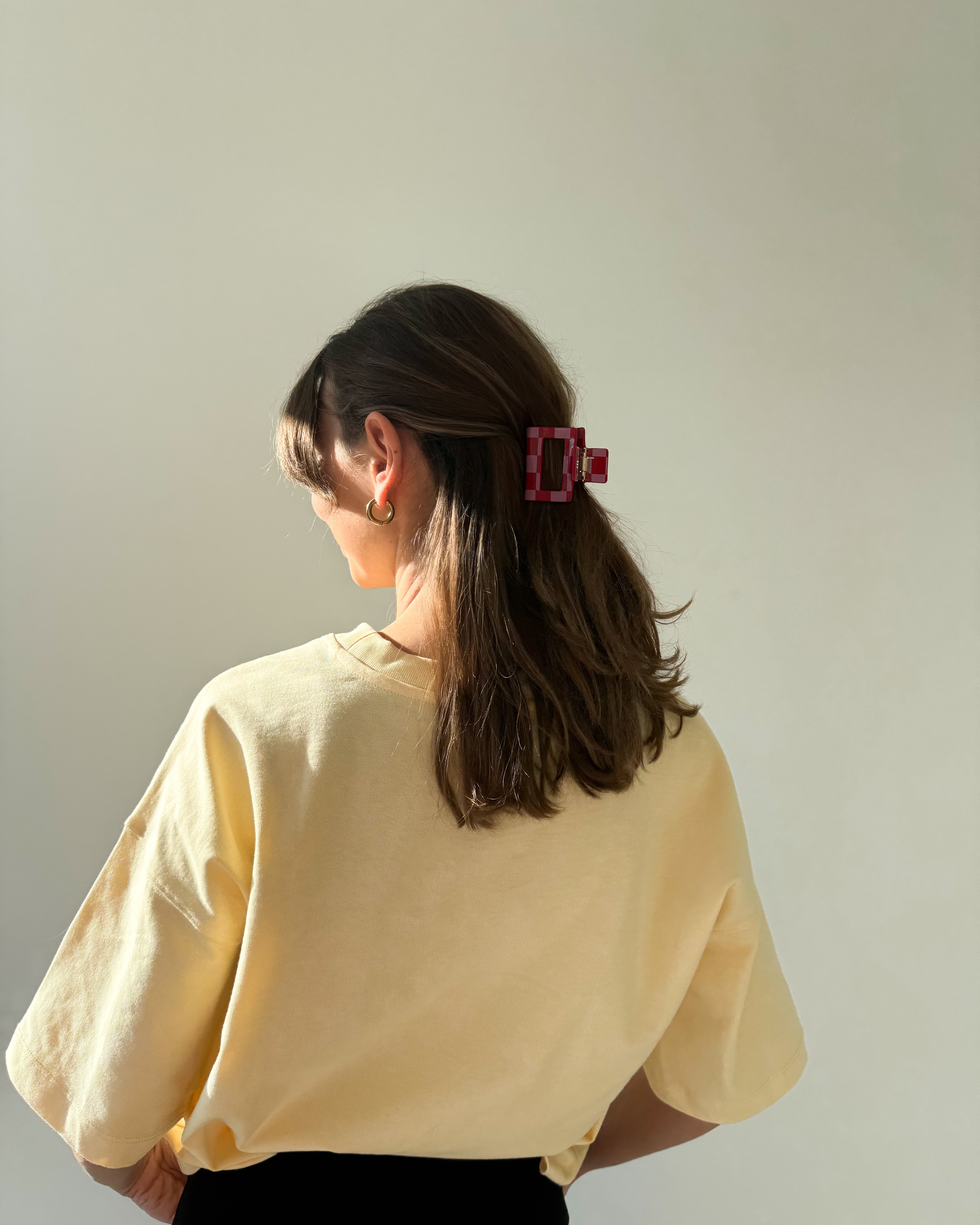 eine frau trägt eine haarklammer aus acetat in der farbe pink/rot