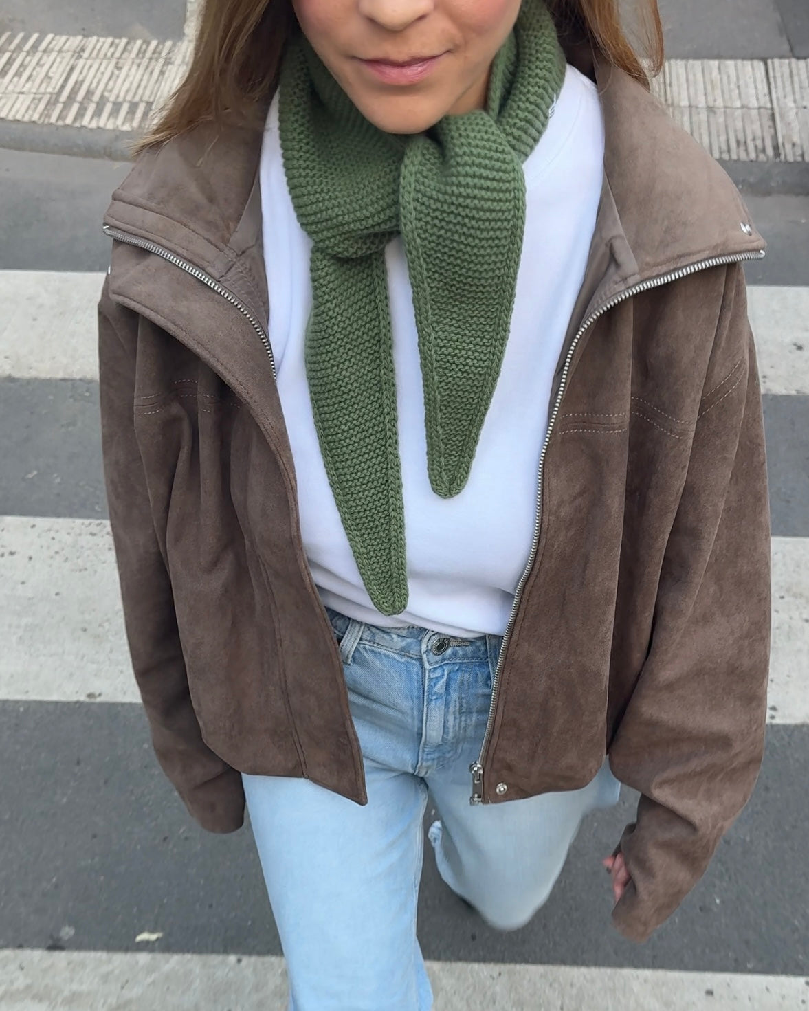 eine frau trägt einen mini schal in grün und geht über die straße