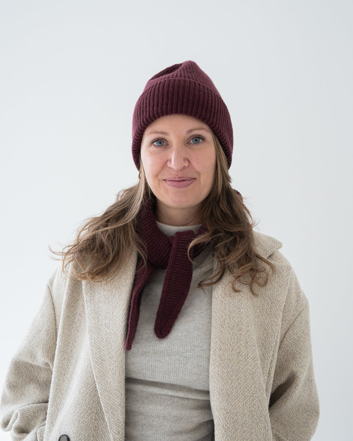 eine frau trägt eine mütze und einen mini schal in der farbe burgundy