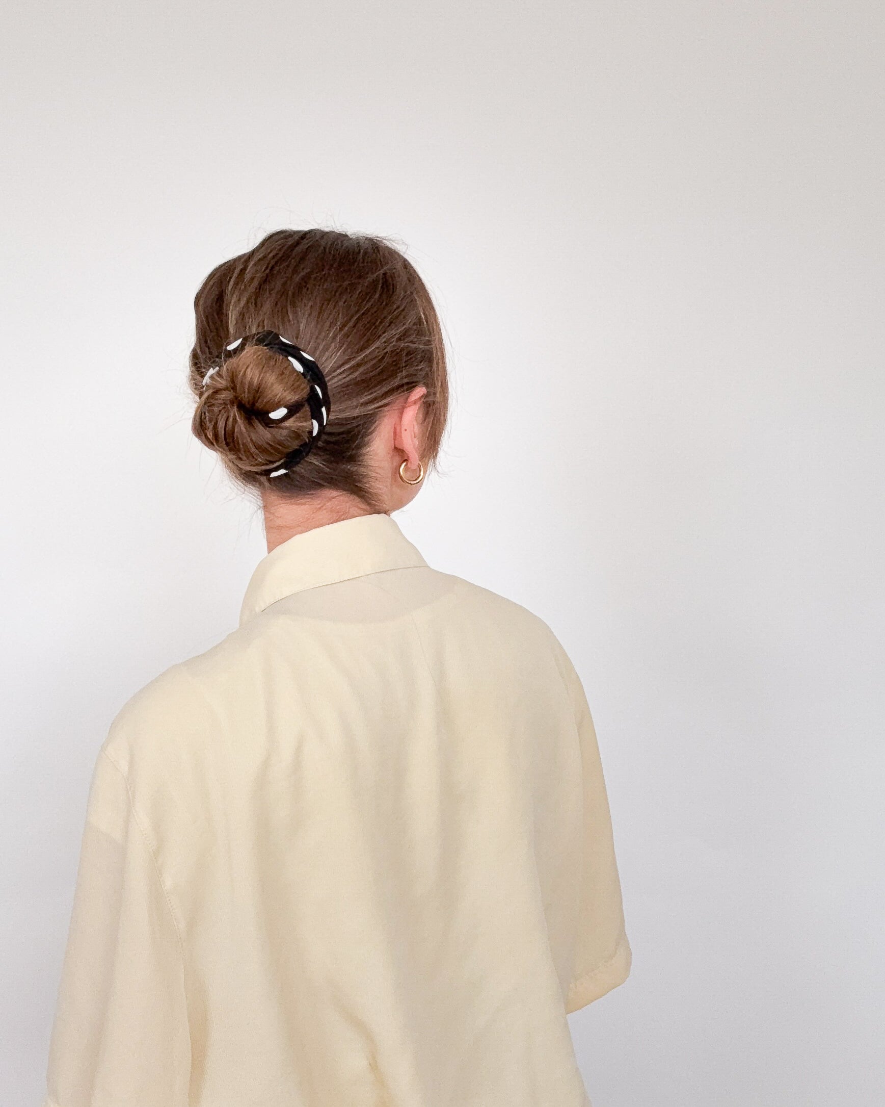 rückansicht einer frau mit längeren haaren, die ein schwarzes drahthaarband im bunstyle trägt