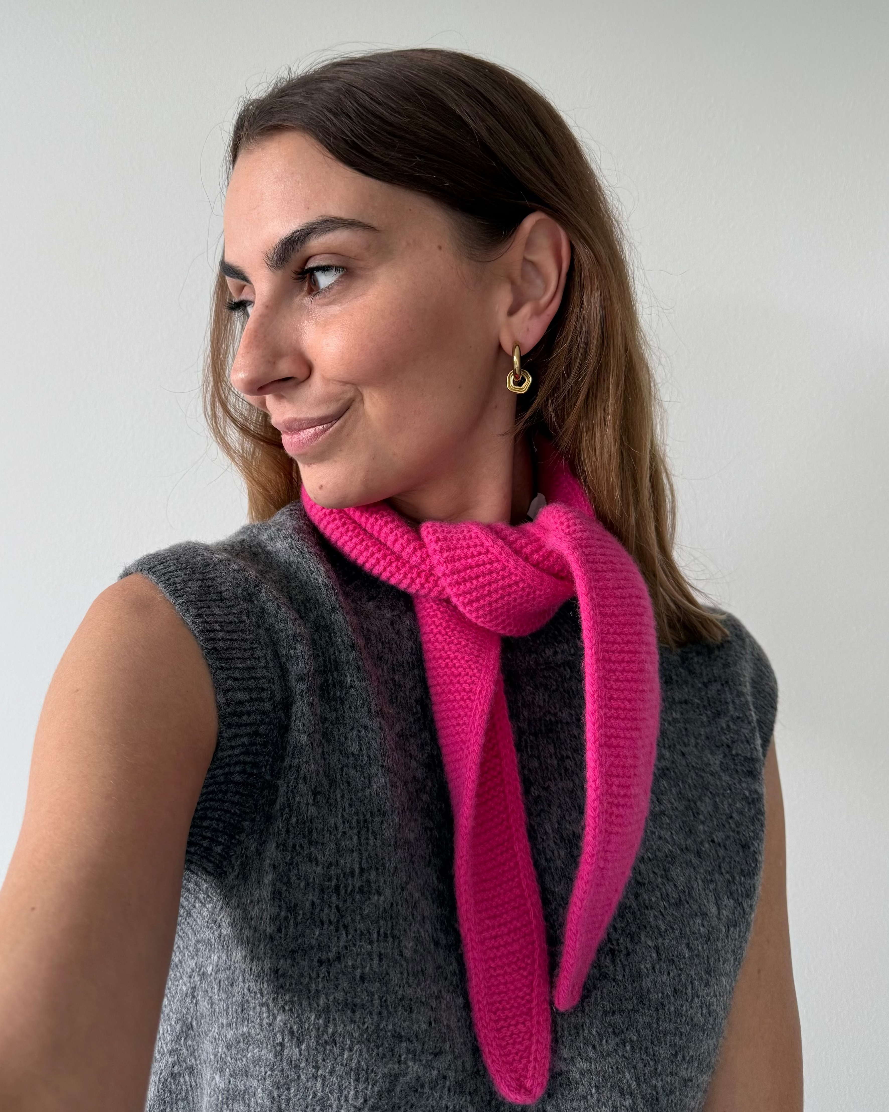 eine frau trägt einen mini schal in pink aus merinowolle