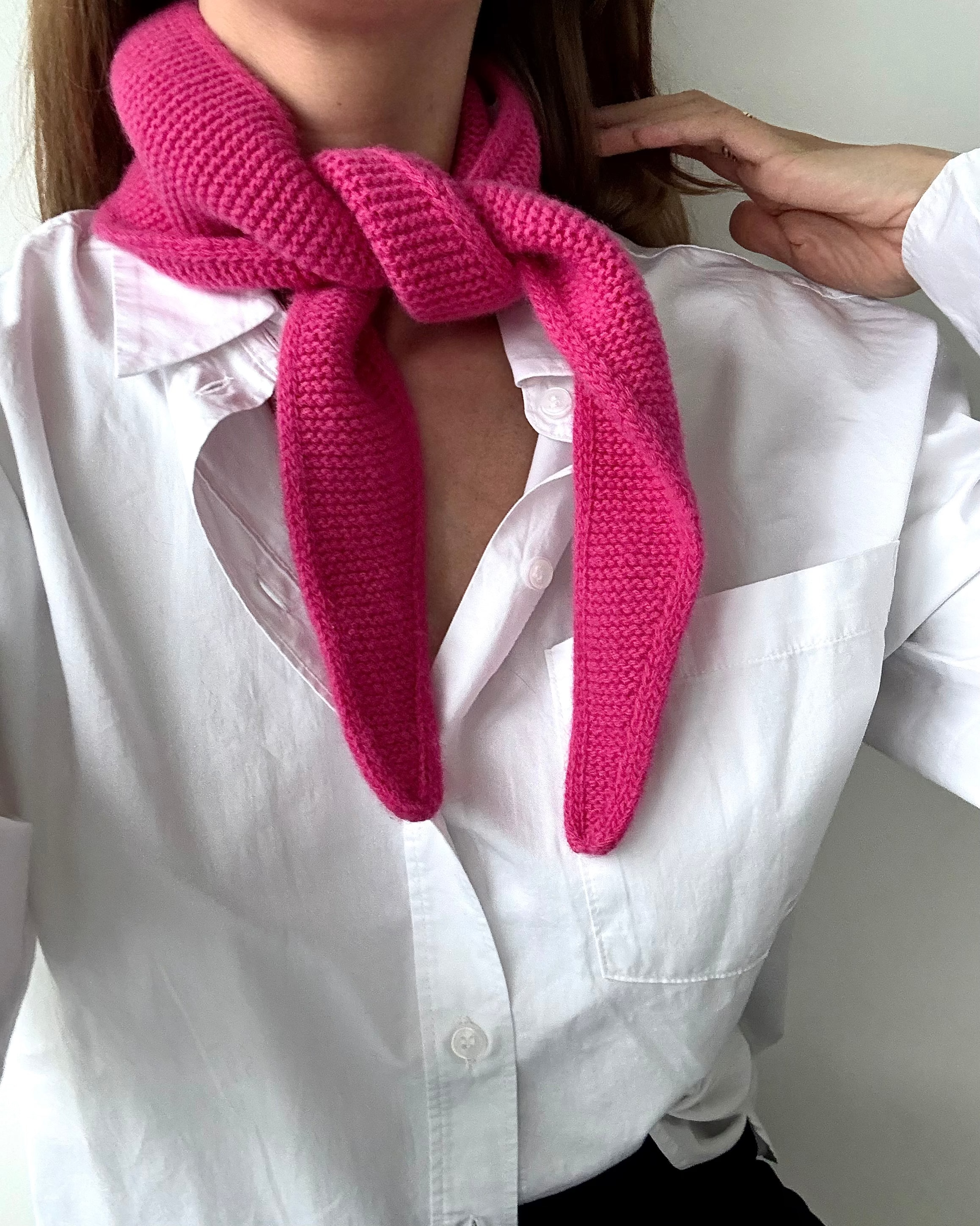eine frau trägt einen mini schal in pink aus merinowolle