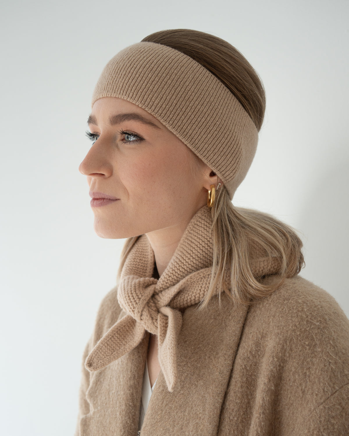 eine frau trägt ein stirnband und einen minischal aus merinowolle in beige